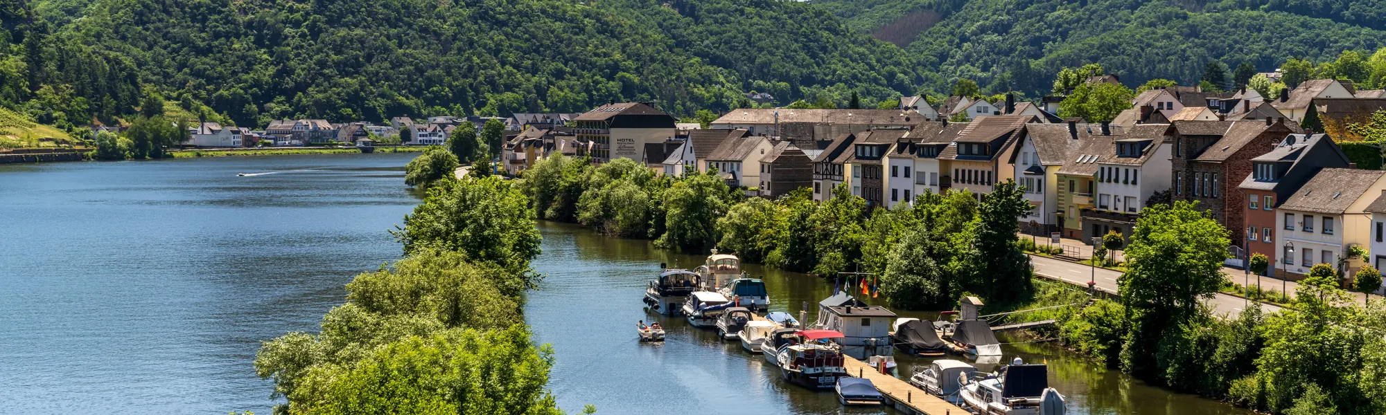 Sportboote am Steg an der Mosel vor einem Weinort