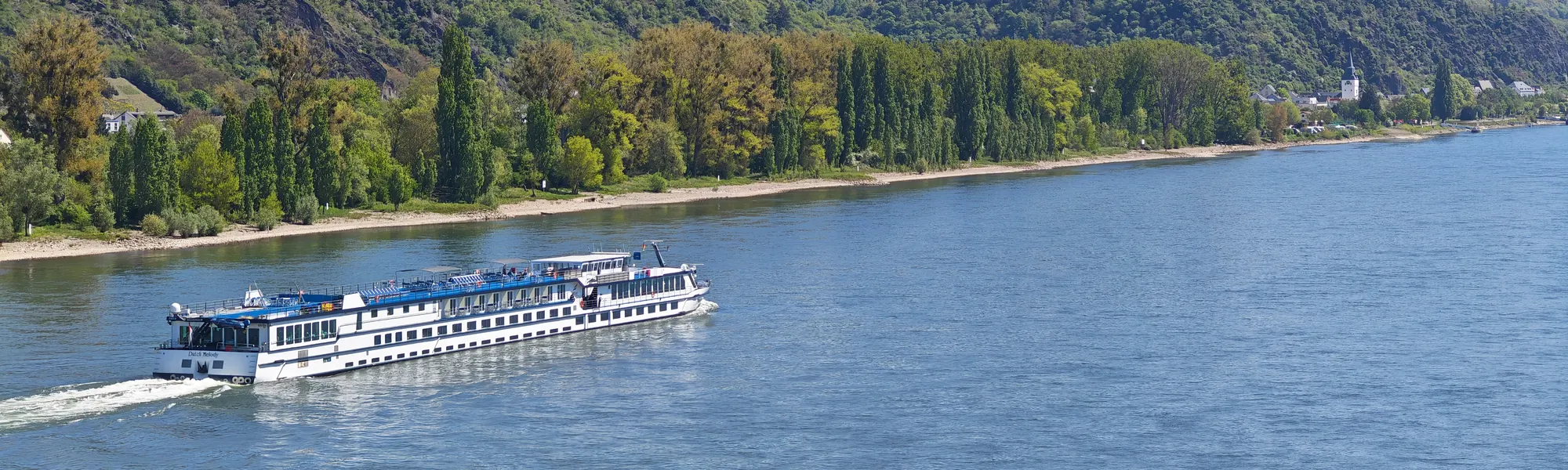 Fahrgastschiff auf dem Rhein vor bewaldeten Hängen